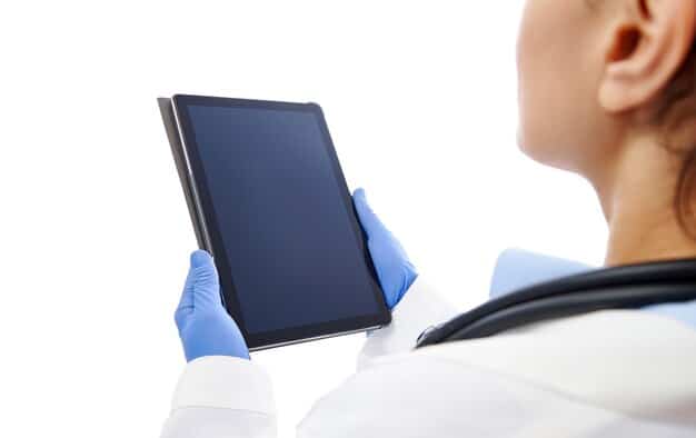 A close-up shot of a doctor's hand using a tablet displaying AI-generated diagnostics for a patient's medical imaging scan. The screen highlights key areas of concern, and the doctor's expression shows focused attention and determination.